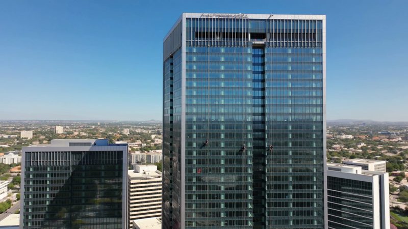 Rope access window cleaners working down the glass facade of an office tower